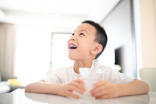 Cheerful Asian boy enjoying a glass of milk.