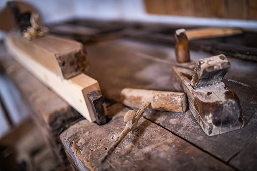 Close-up of plane and gimlet with wooden plank on table in workshop.