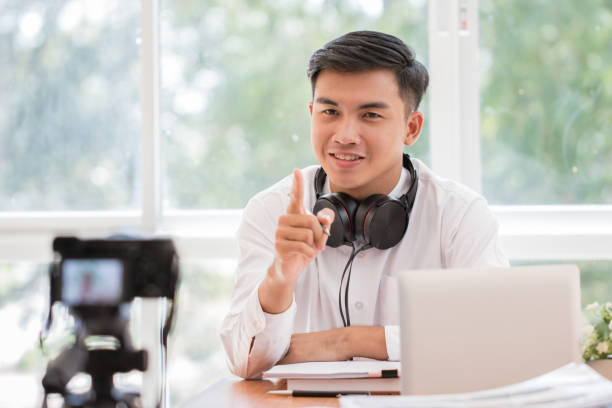 Happy Asian businessman videoblog / blogger vlogger recording online course or tutorial strategy presentation pass video for teaching live marketing sharing social media channel by mirrorless camera