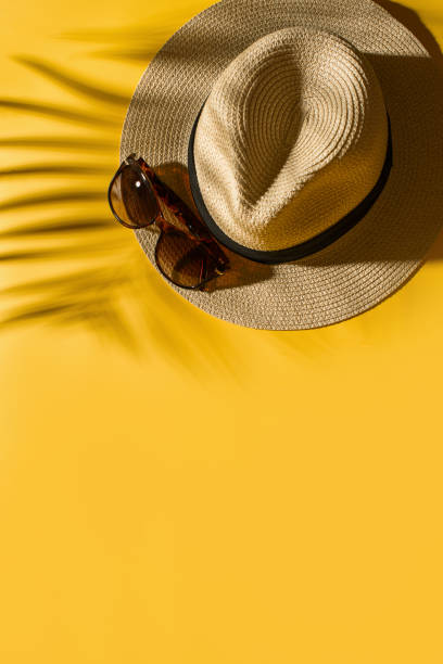 istock Hat and glasses on bright yellow background with tropical leaf shadow, creative pastel, beach concept 1157938771