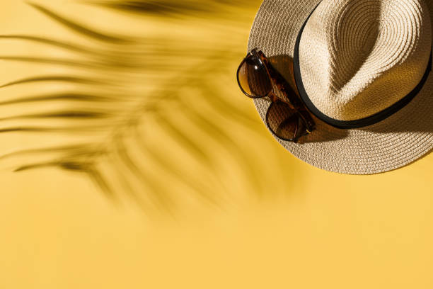 istock Hat and glasses on bright yellow background with tropical leaf shadow, creative pastel, beach concept 1157938795