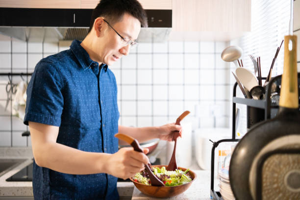 istock Asian man making salad at home 1157938959