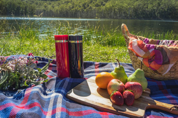 couple having picnic on sunny day weekend in Autumn with baguette sandwich fruits wine picnic basket bring my bottle stock photo