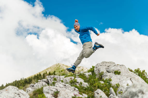 istock Male hiker jumping on a rocky mountain 1157941244