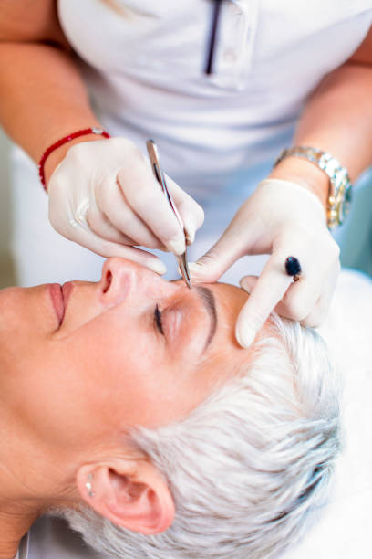 istock Elderly, white-haired woman getting her eyebrows professionally angled in a cosmetic salon 1157942808