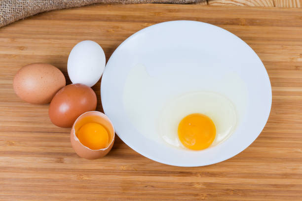 istock Whole and broken eggs on dish on a wooden surface 1157945041