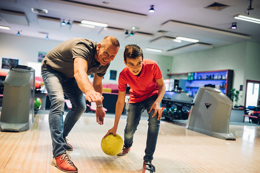 Happy young boy bowling with his father