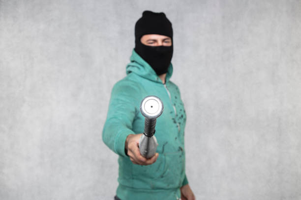 thief with balaclava and tattoos on white background. Person stealing photo camera. Crime and delinquency. Home security and insurance.