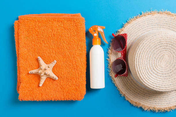 istock Summer beach flat lay accessories. Sunscreen bottle cream, towel and seashells on colored Background. Travel holiday concept with copy space 1157948900