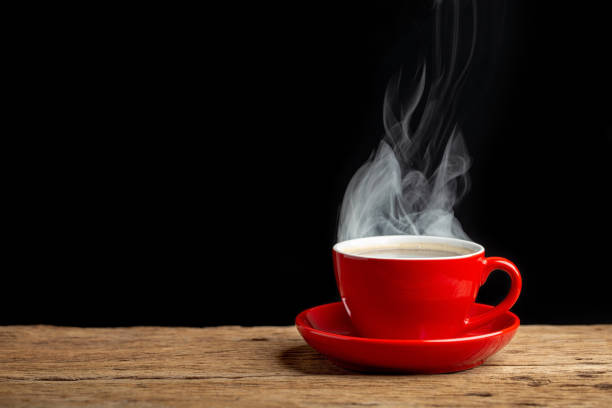 hot coffee in red cup on old wooden table with black wall background. stock photo