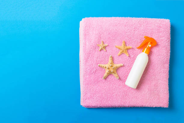 istock Summer beach flat lay accessories. Sunscreen bottle cream, towel and seashells on colored Background. Travel holiday concept with copy space 1157949464
