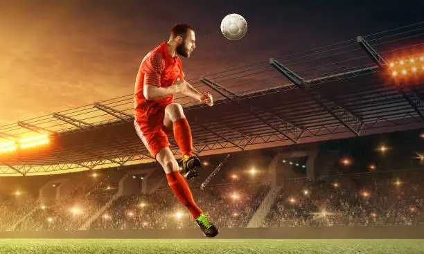 Professional soccer player makes head shot. Night soccer stadium with fans cheering and dramatic sky. Sports event