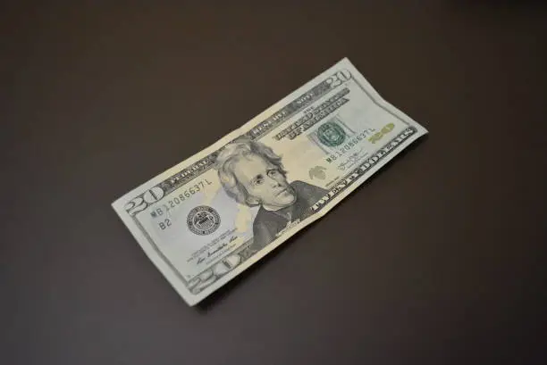 Photo of American cash, currency, twenty dollars located on a matte brown background. Financial market, profit from work and business.