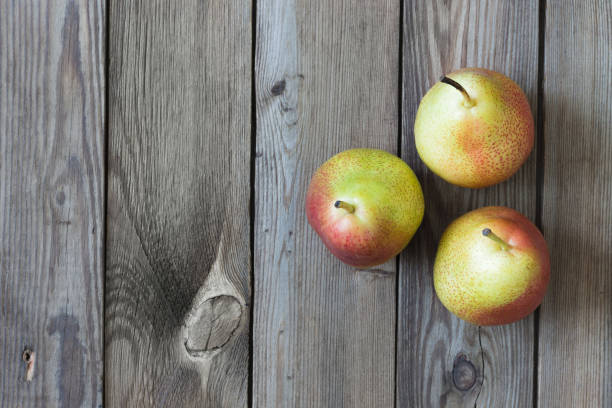 A close-up shot of a rustic wicker basket filled with fresh fruits, including apples and pomegranates, adorned with dewdrops. The basket is set against a warm, wooden background, giving the image a cozy, autumnal feel. Perfect for use in food, rustic lifestyle, and seasonal-themed advertising or editorial projects