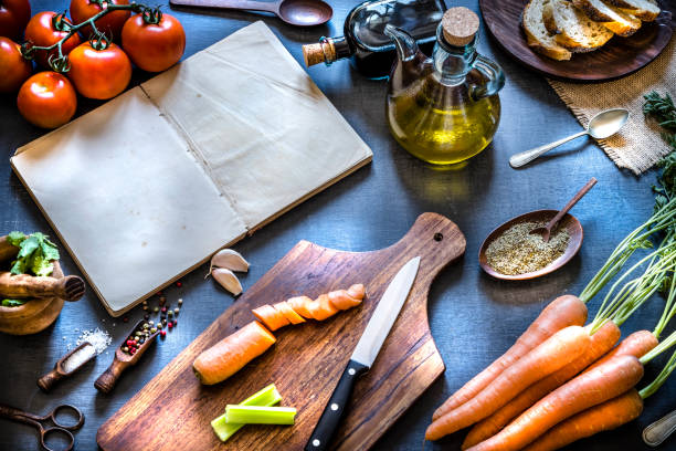 istock Cookbook with vegetables and seasoning spices on dark kitchen table 1157954219