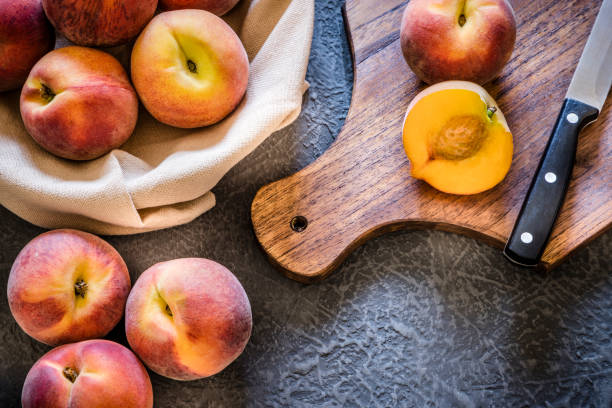 Whole and sliced peaches on dark gray textured background