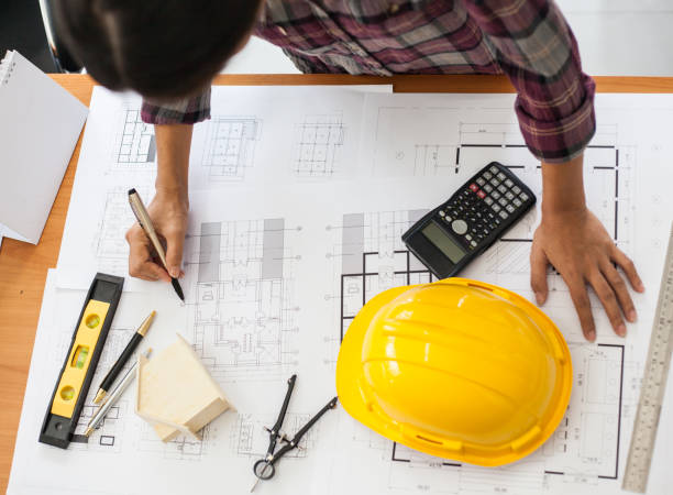 istock Engineers or architect holding a pen with drawings 1157955894