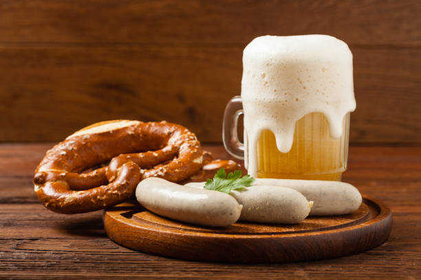 Boiled white sausage, served with beer and pretzels. Perfect for Octoberfest. Boiled white sausages, served with beer and pretzels. Perfect for Octoberfest. Natural wooden background. Front view. oktoberfest food stock pictures, royalty-free photos & images