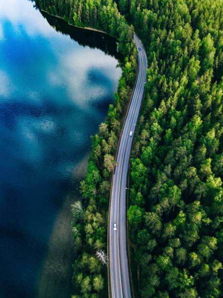 vista aérea de la carretera entre el bosque verde y el lago azul en finlandia - pine wood forest river fotografías e imágenes de stock