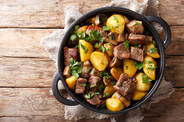 patatas fritas tradicionales con carne de cerdo y champiñones de cerca en una sartén. vista superior horizontal - healthy eating food vegetable fungus fotografías e imágenes de stock