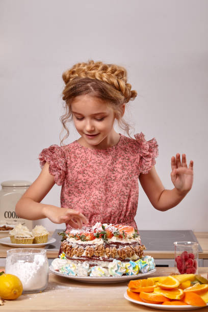 niña está haciendo un pastel casero con una receta fácil en la cocina contra una pared blanca con estantes en él. - beauty beautiful braids dairy product fotografías e imágenes de stock