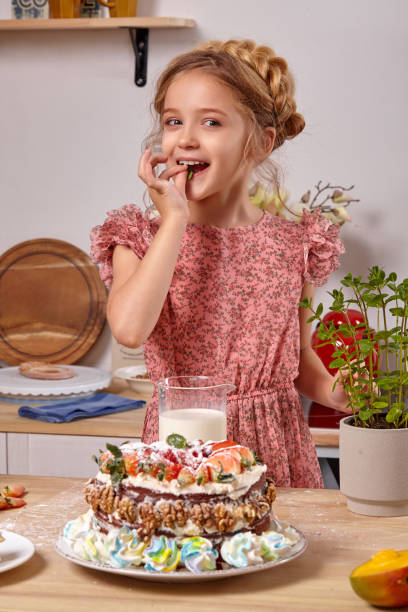 маленькая девочка делает домашний торт с легким рецептом на кухне против белой стены с полками на нем. - beauty beautiful braids dairy product стоковые фото и изображения
