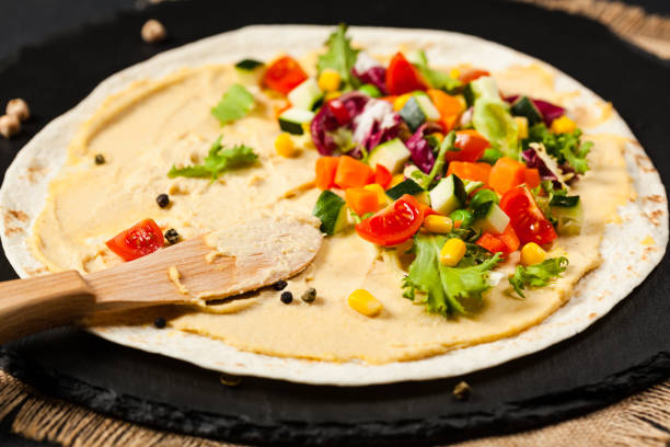 Tortilla with vegetables and hummus with chickpeas. Tortilla with vegetables and hummus with chickpeas. Front view. black shawl wrap stock pictures, royalty-free photos & images