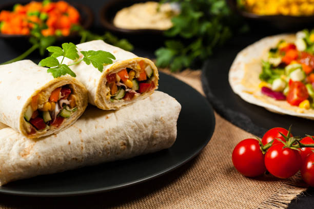 Tortilla with vegetables and hummus with chickpeas. Tortilla with vegetables and hummus with chickpeas. Front view. black shawl wrap stock pictures, royalty-free photos & images