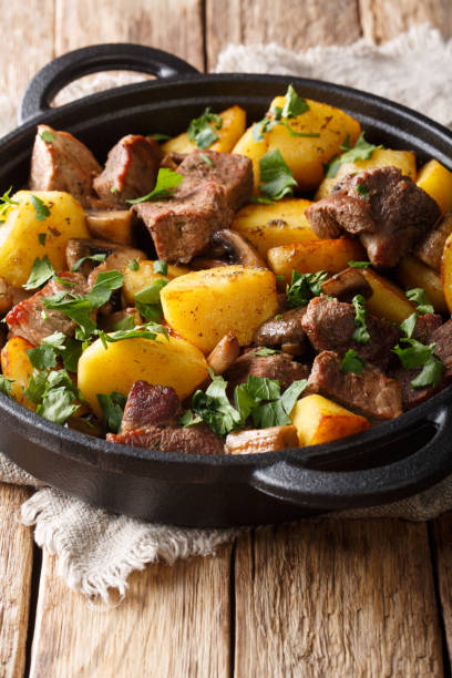 istock Rustic style fried pork with potatoes and mushrooms close-up in a pan. vertical 1157958031