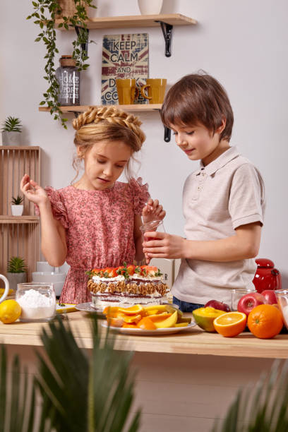 los pequeños amigos están haciendo un pastel juntos en una cocina contra una pared blanca con estantes. - beauty beautiful braids dairy product fotografías e imágenes de stock