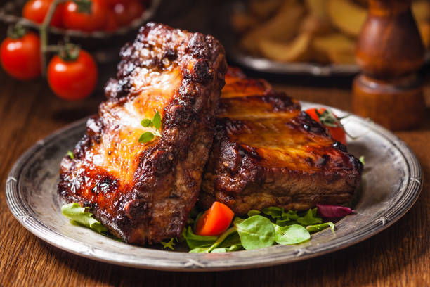 costillas asadas, servidas en un plato viejo. fondo oscuro o balck. - costilla fotografías e imágenes de stock