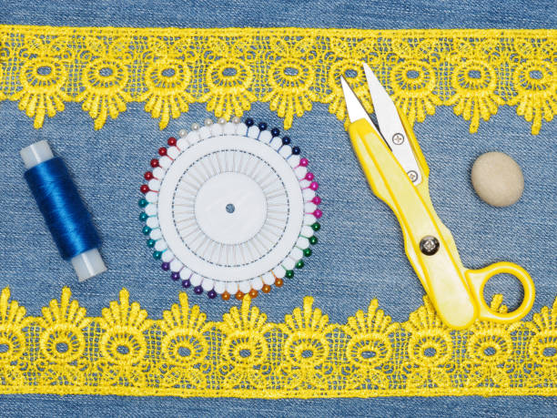 istock Yellow lace, thread, pins, scissors on a jeans background. Sewing still life 1157963749