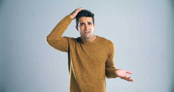 How did that happen? Studio shot of a handsome young man scratching his head in confusion against a gray background fool stock pictures, royalty-free photos & images