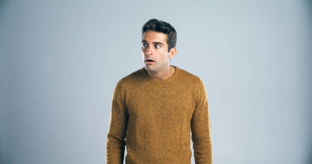 What...is...that?? Studio shot of a handsome young man looking scared against a gray background worried man standing stock pictures, royalty-free photos & images