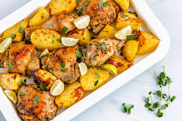 pieczony kurczak i ziemniaki na blasze pan przyozdobiony świeżymi liśćmi oregano bezpośrednio nad zdjęciem. - greek cuisine chicken grilled grilled chicken zdjęcia i obrazy z banku zdjęć