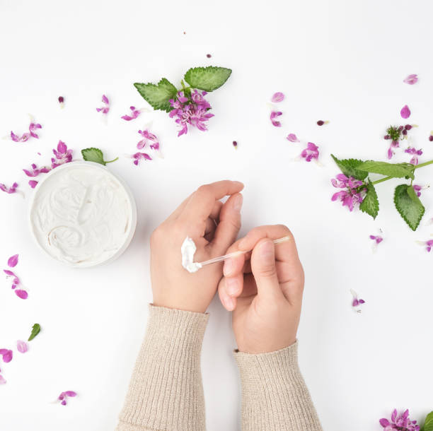 istock two female hands and a jar with thick cream and pink flowers 1157968232