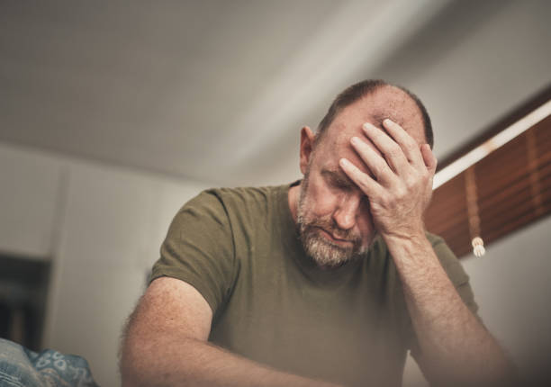 Tired and despairing mature man in his bedroom in the morning It's a bleak morning for a middle-aged man. head in hands stock pictures, royalty-free photos & images