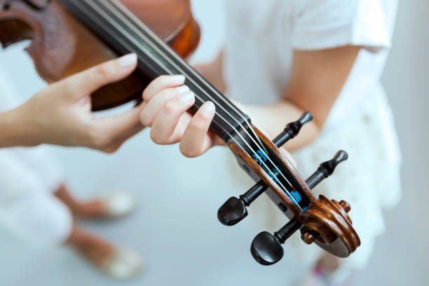 istock Teacher's hands help kid's hand to play the violin 1157972260