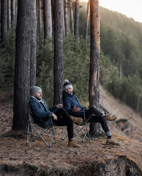 istock Men sitting in folding chairs on forest cliff 1157972388