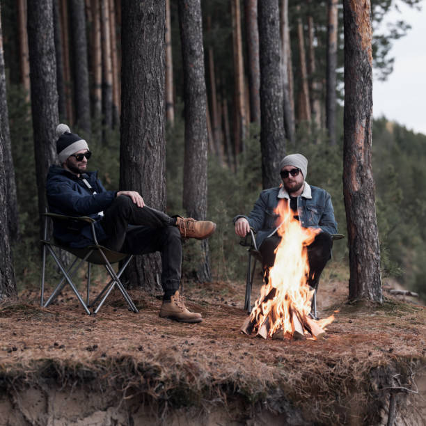 istock Stylish male friends relaxing by campfire 1157972484