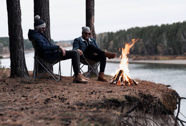 istock Male friends resting around bonfire by river 1157972531