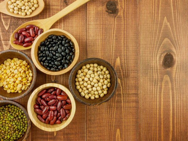 Flat lay,top view assorted beans including red bean,soybeans,black beans,mung beans on brown,beige wooden background with copy space