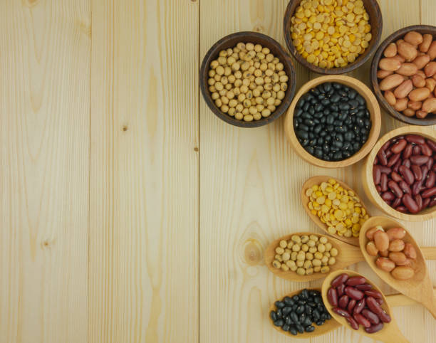 Flat lay,top view assorted beans including red bean,soybeans,black beans,mung beans on brown,beige wooden background with copy space