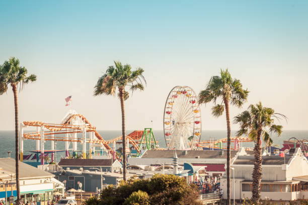 Famous amusement park with ferris wheeil in Santa Monica Los Angeles California in pastel ligt of sunset. Focus on palms