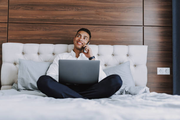 istock Happy young man is enjoying phone conversation in bedroom 1157979677