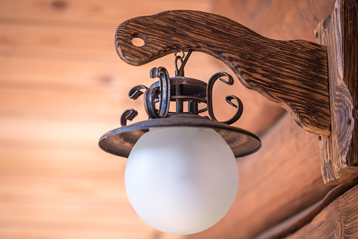 glass ball on a wooden handle retro street lamp hanging on the wall in wooden house