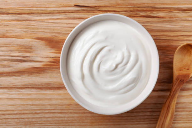 istock Greek yogurt in white bowl on wooden table top view. 1157980054