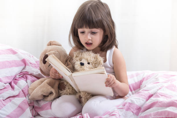 istock Cute little girl smiling while lying in a cozy white bed 1157980127