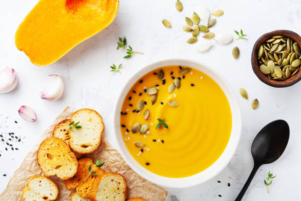 ボウルの秋のカボチャクリームスープは、白い石のテーブルトップビューに種子とクルトンを添えました。 - thanksgiving vegetarian food pumpkin soup ストックフォトと画像