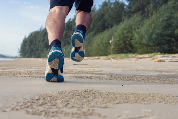 istock Man run on the beach, closeup on shoes 1157981357